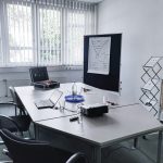 Ein Raum für Besprechungen und Meetings ausgestattet mit einem Beamer, Flipchart, Whiteboard, Moderationskoffer, einem Tisch und Stühle.